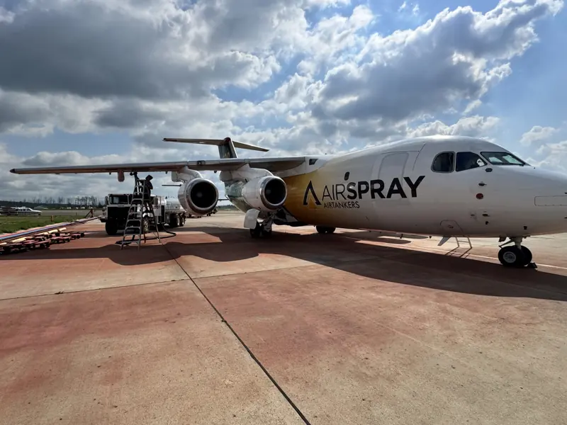 An Airspray BAe 146 air tanker parked on a concrete apron under a cloudy sky